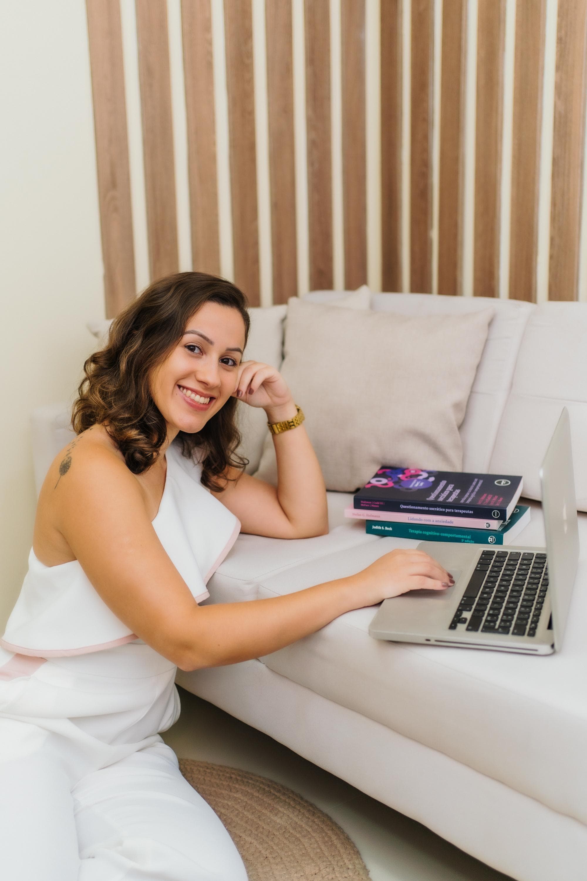 Myllena Barbosa em atendimento online, ao lado de livros de terapia cognitivo-comportamental